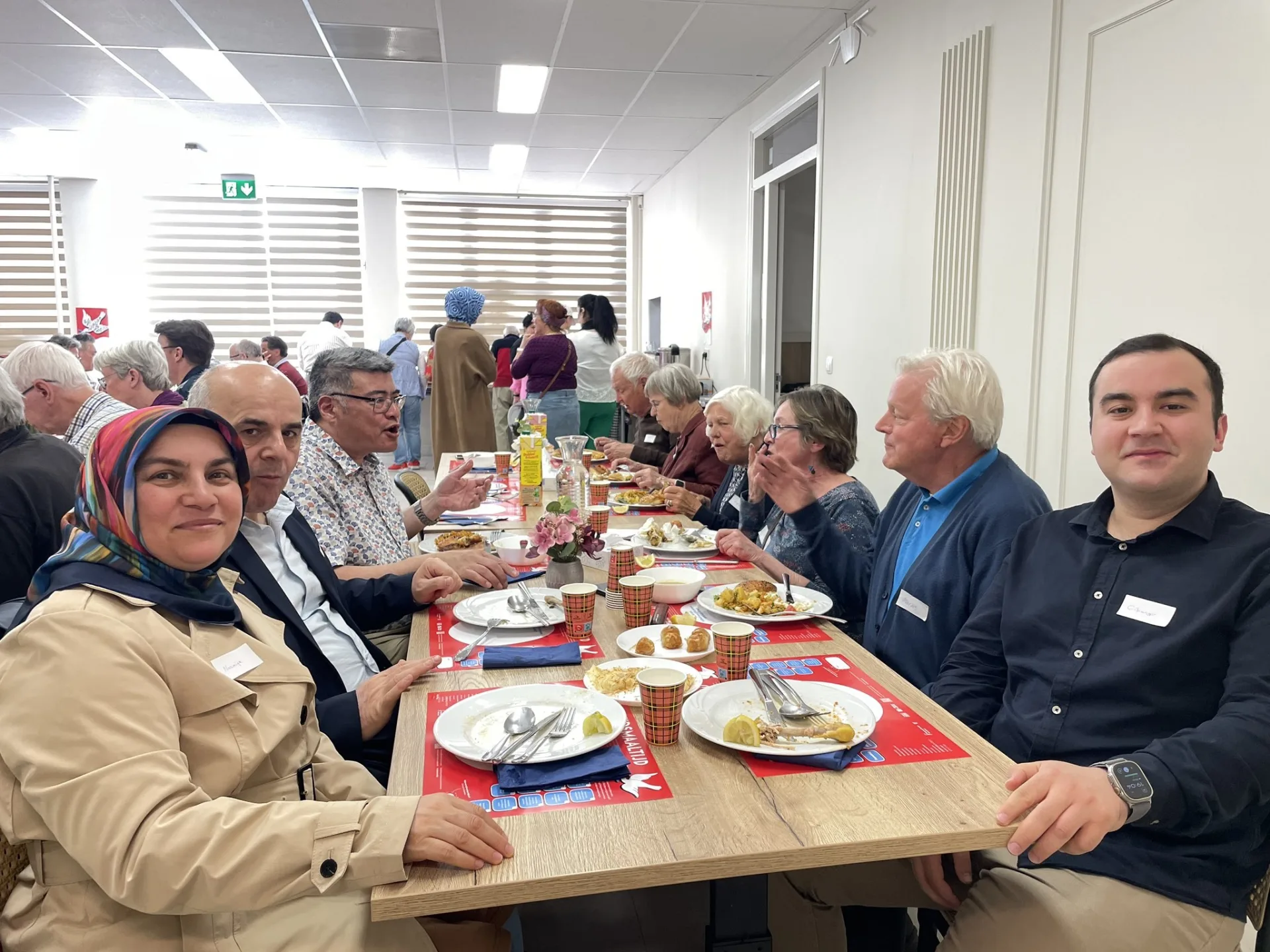 Gasten aan lange tafels tijdens de Vrijheidsmaaltijd op 5 mei bij SEVA
