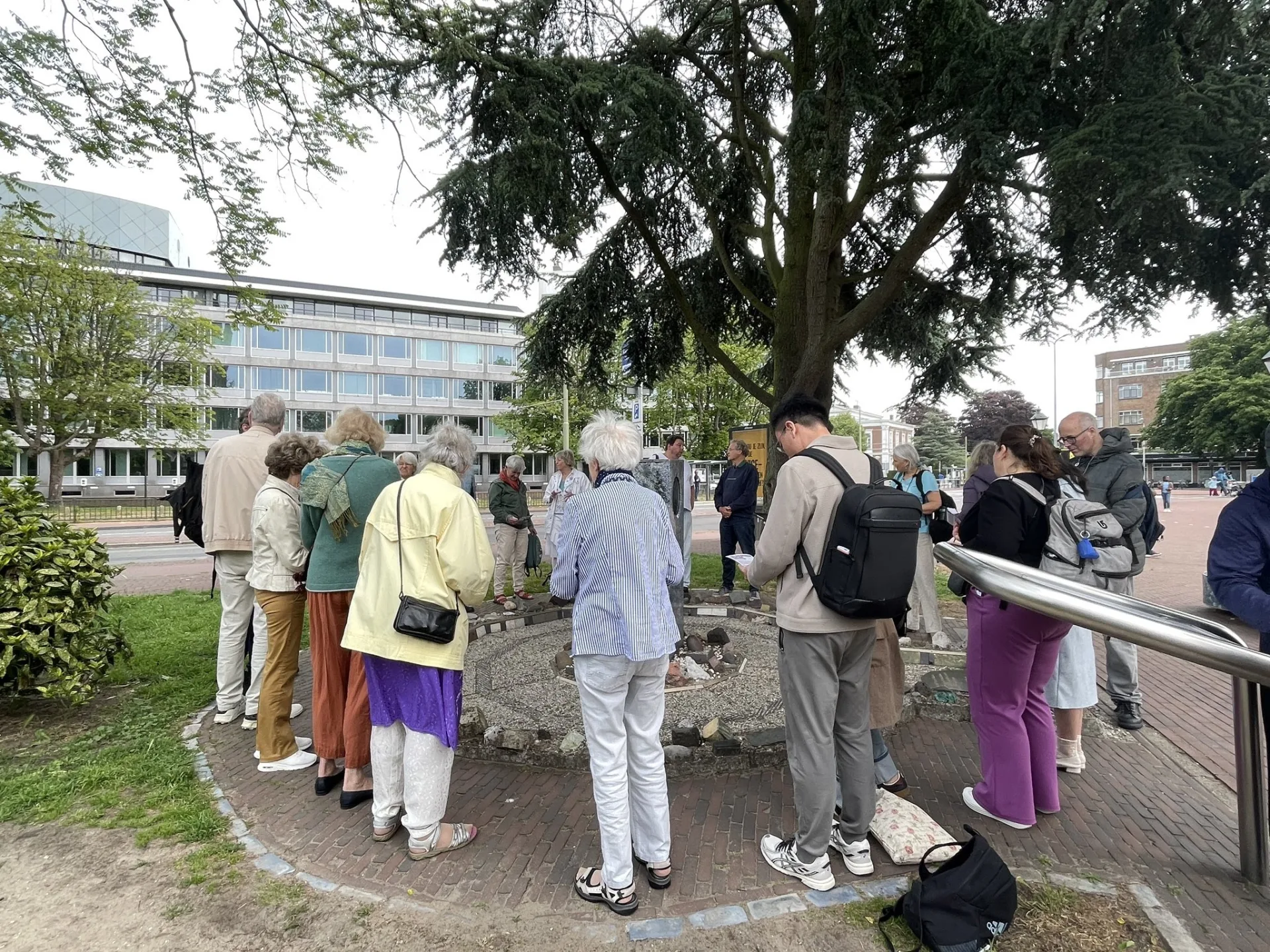 Deelnemers van verschillende levensbeschouwingen in een kring bij de Vredesvlam bij het Vredespaleis