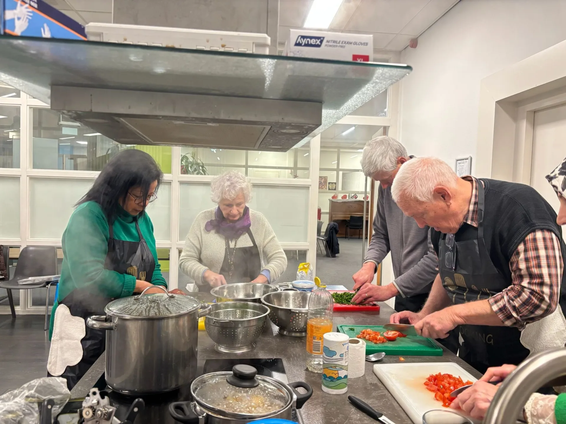 Cursisten koken samen aan het fornuis tijdens de kookworkshop