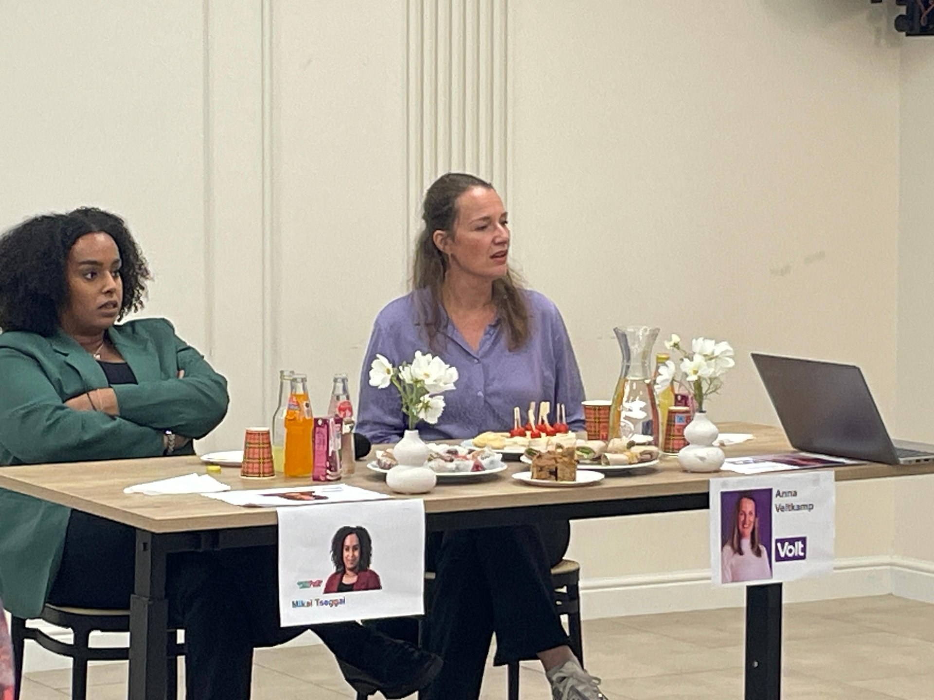 Twee lokale politici in gesprek met bezoekers tijdens een kennismaking bij SEVA