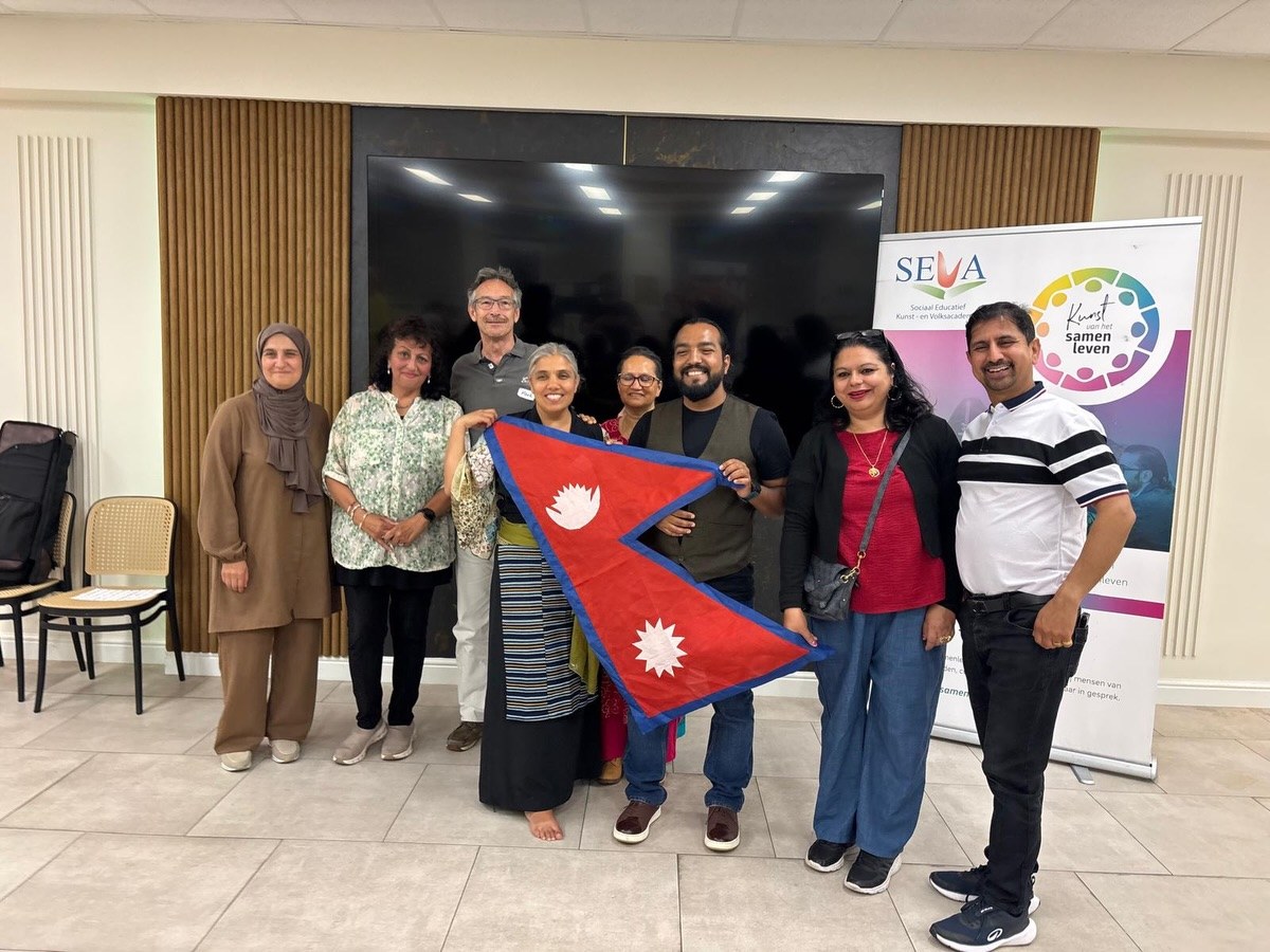 Gasten en vrijwilligers samen met de vlag van Nepal