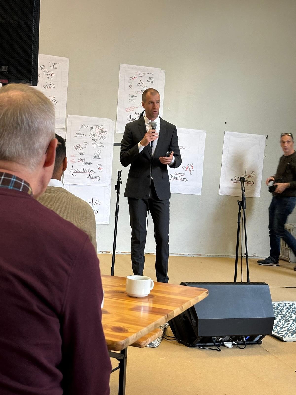 Een spreker met een microfoon bij de opening van Weimarstraat 300