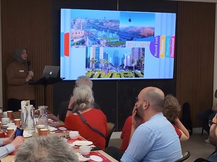 Een spreker met een presentatie voor de gasten aan tafel tijdens de Vrijheidsmaaltijd